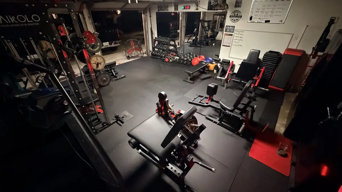 Wide view of the garage gym with red and black strength machines